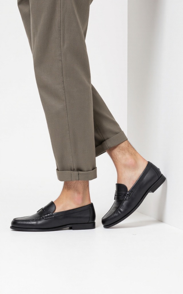 A male model wearing Loafers, against a white background, with a close   up of the feet